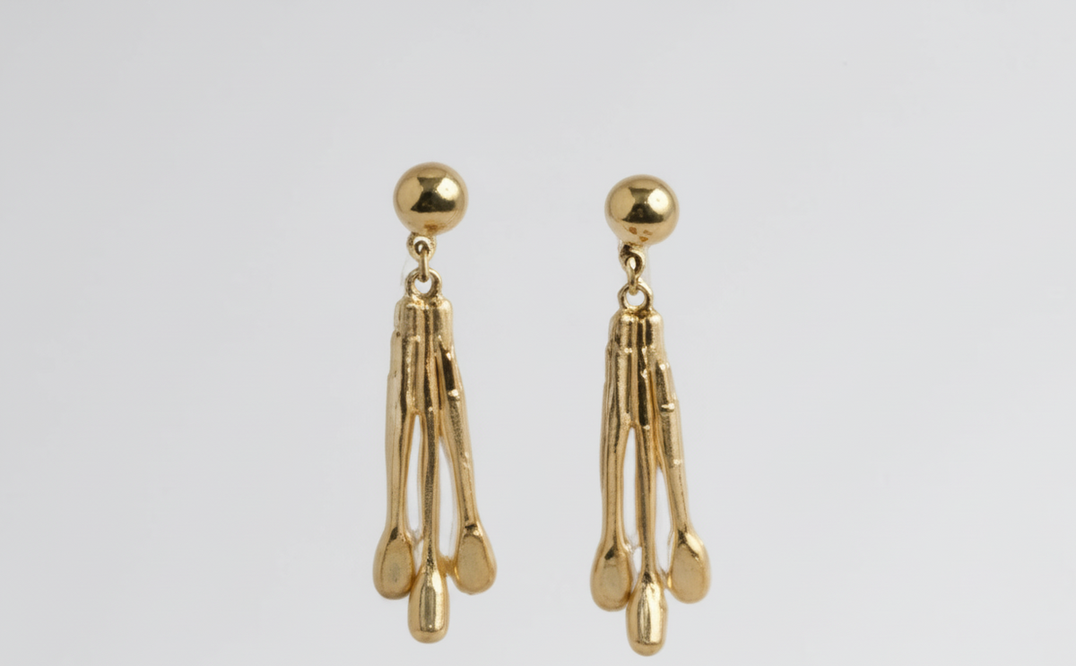 Close-up of hammered 18K gold-plated brass statement earrings with tapered fringe design, photographed on a model. ZoharasVogue