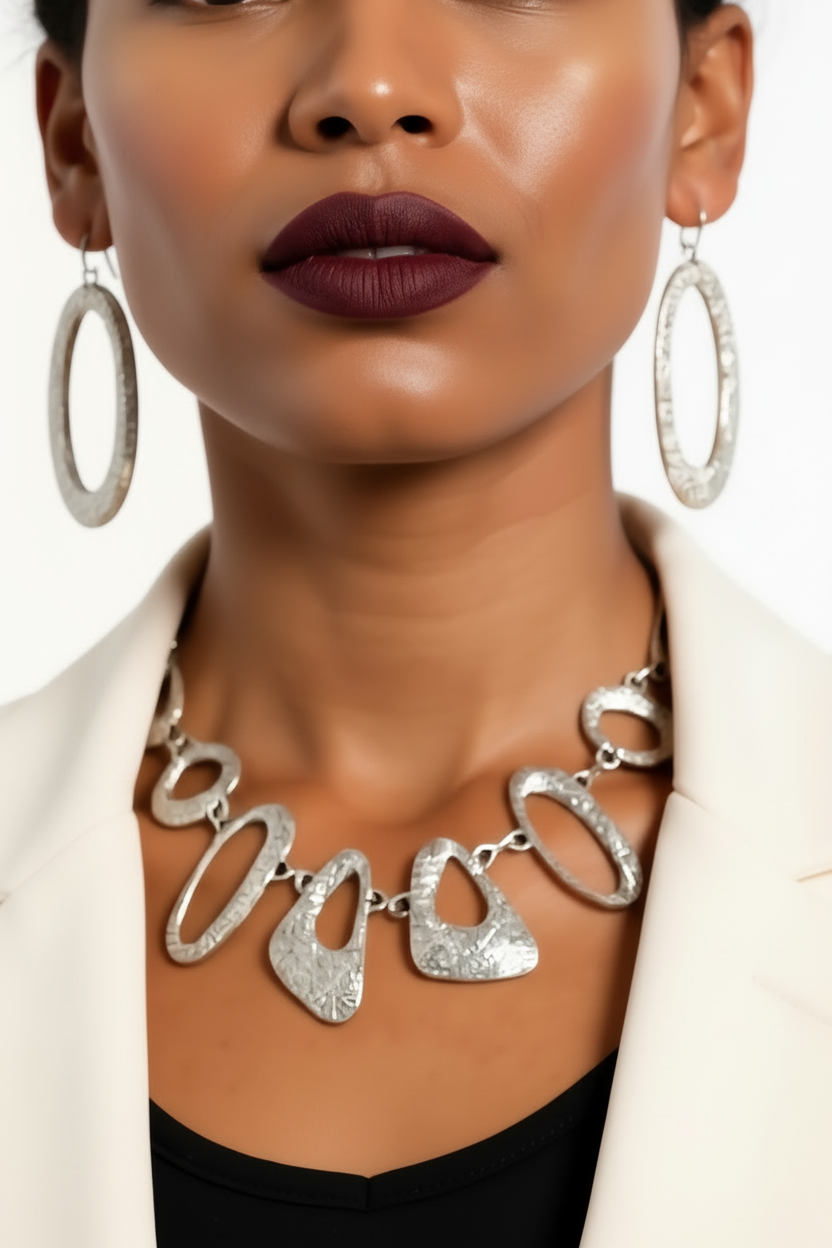Close-up of a woman wearing a silver necklace and hoop earrings with a blurred background
