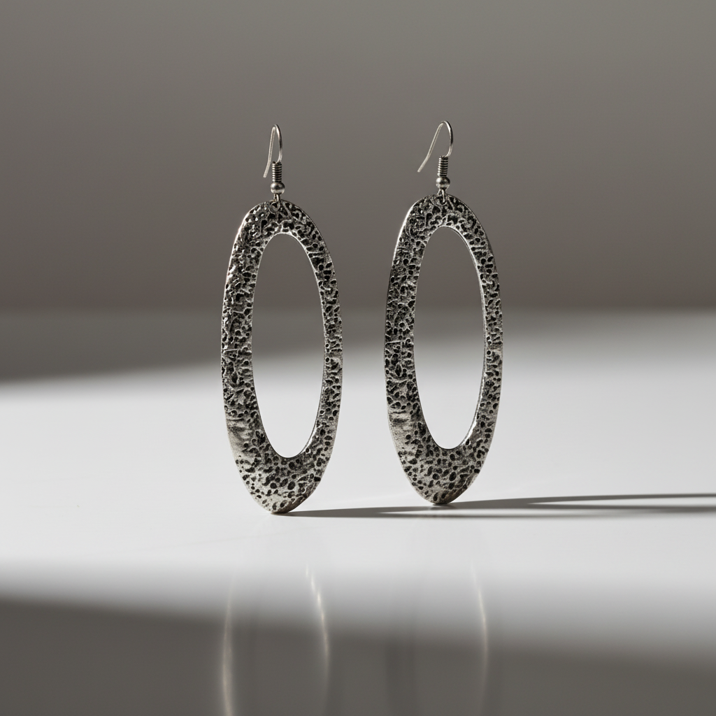 Pair of silver earrings on a reflective surface with a gradient background