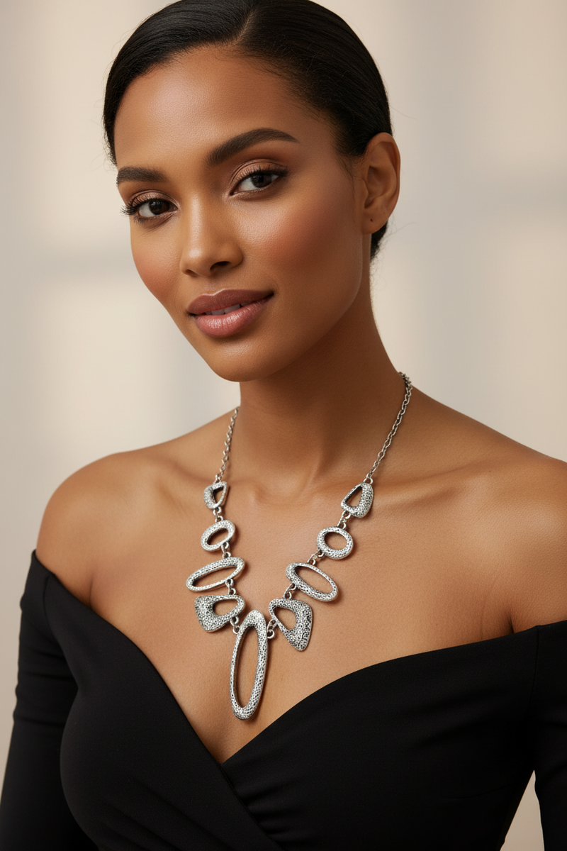 Midel wearing a silver handcrafted starement necklace against a neutral background