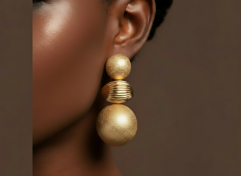 A pair of Calia Matte Sculpted Drops Earrings — geometric tiered matte gold earrings with a striped texture and sculptural form, styled for modern elegance.