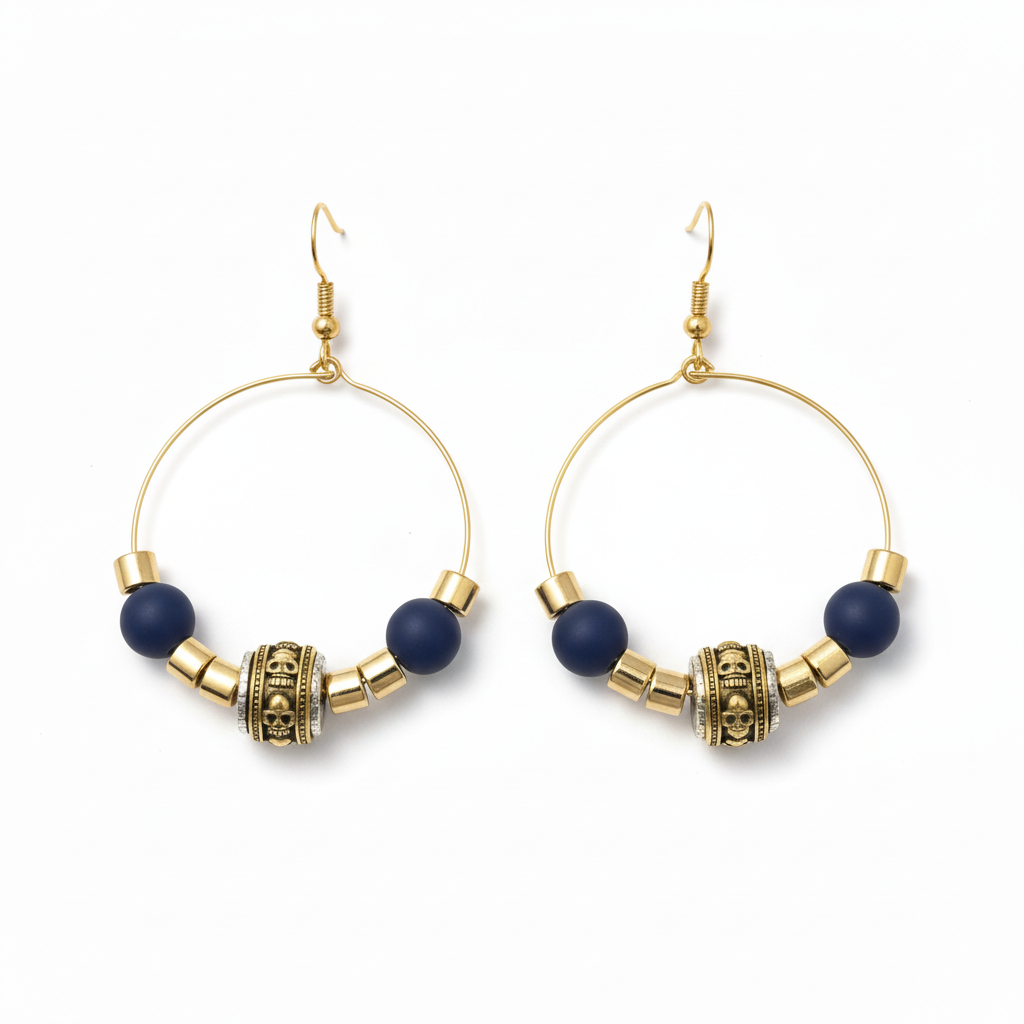 Gold wire hoop earrings with matte navy beads, ornate gold barrel bead, and gold spacer beads, shown on a textured neutral surface.