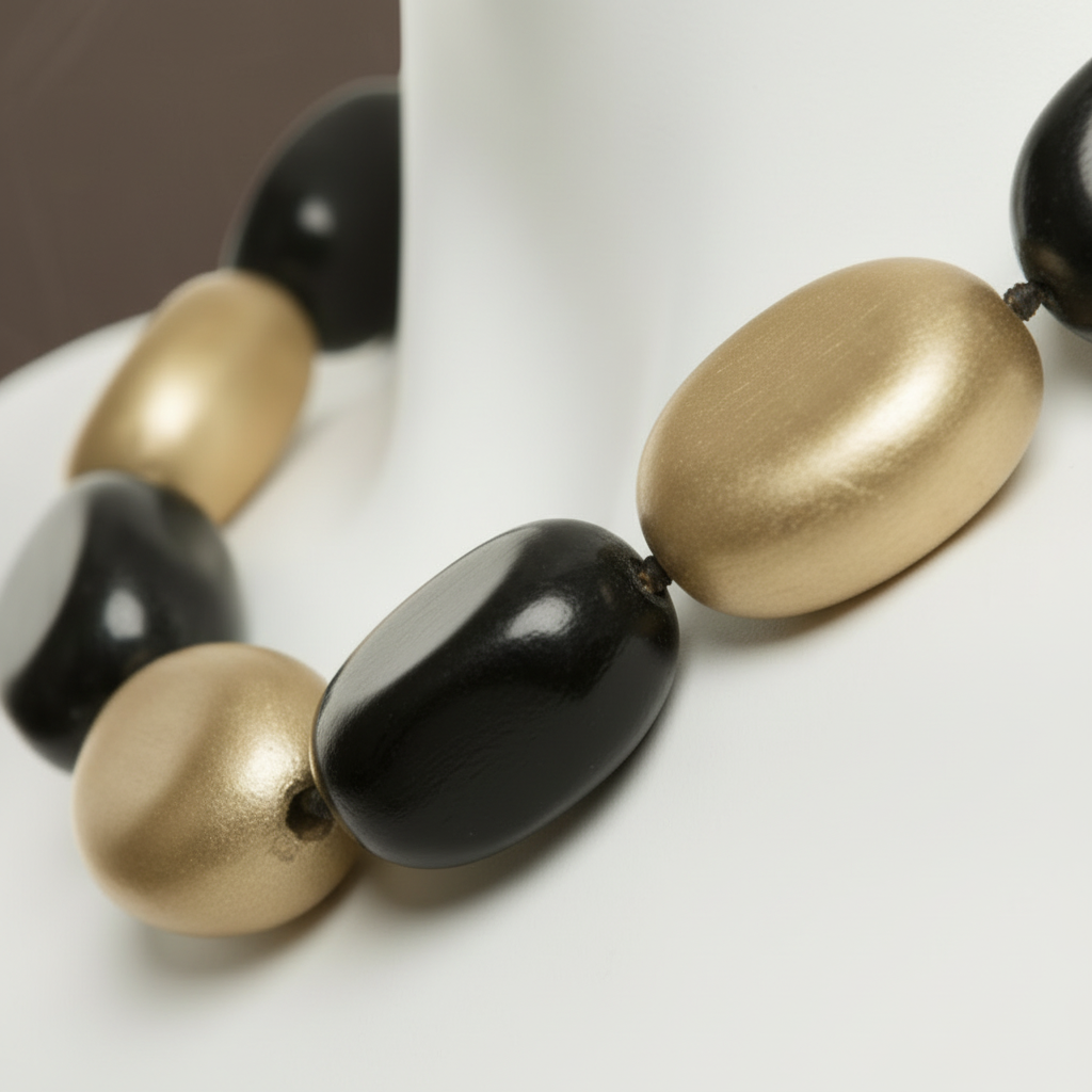 The Dior Statement Earrings, a chunky beaded necklace with alternating black and matte gold beads on a marble surface. ZoharasVogue
