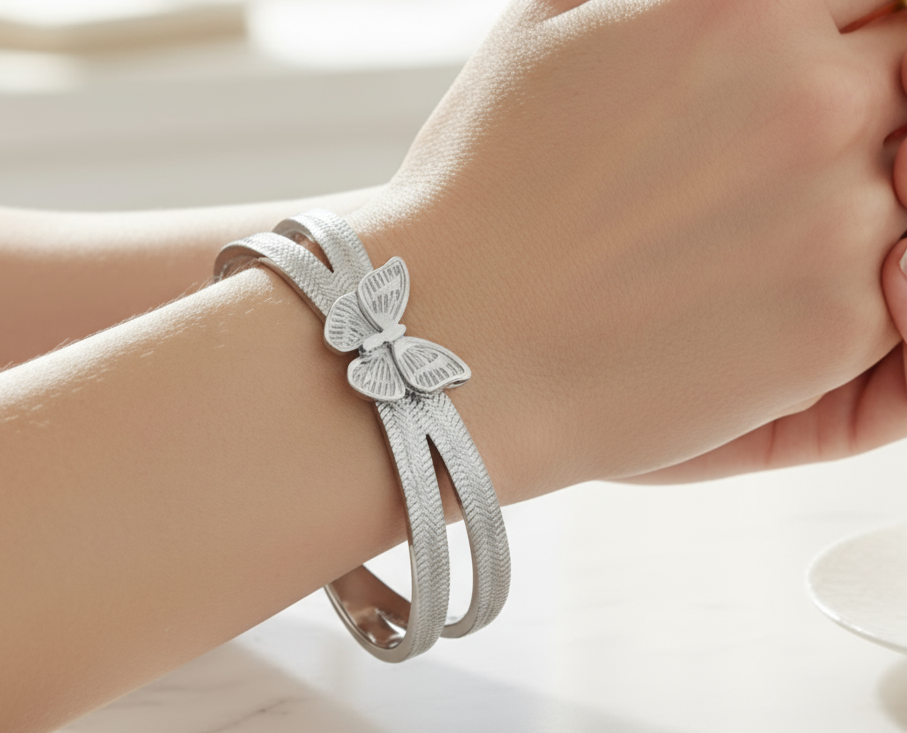 Silver bracelet with butterfly design on a wrist against a blurred. Zoharas Vogue