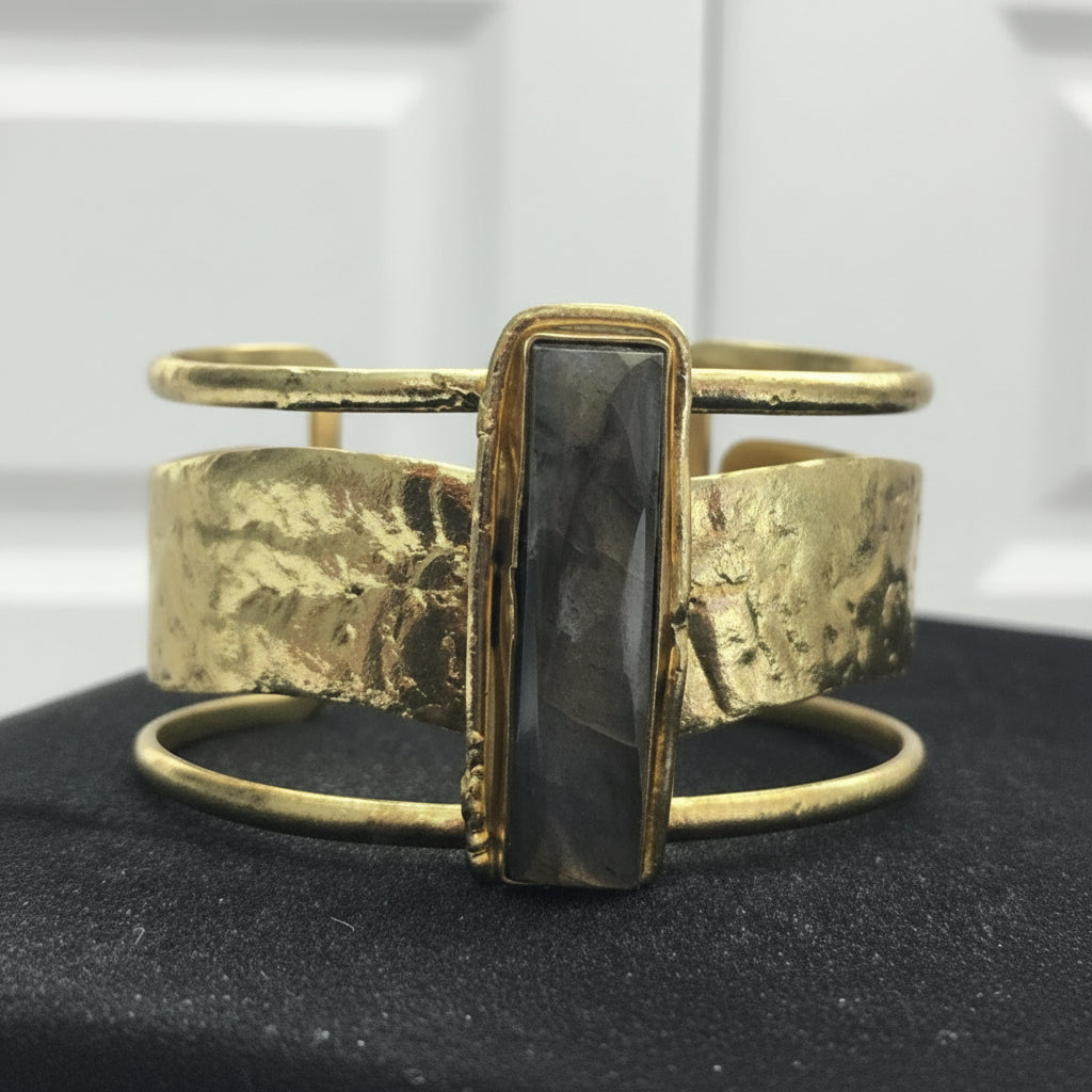 Gold bracelet with a central stone on a black surface_ZoharasVogue