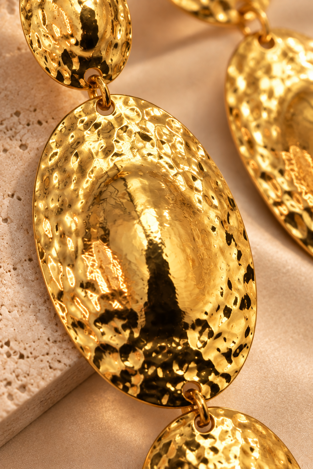 Moana Radiance oversized hammered gold statement earrings with three graduated oval drops and a reflective textured finish.