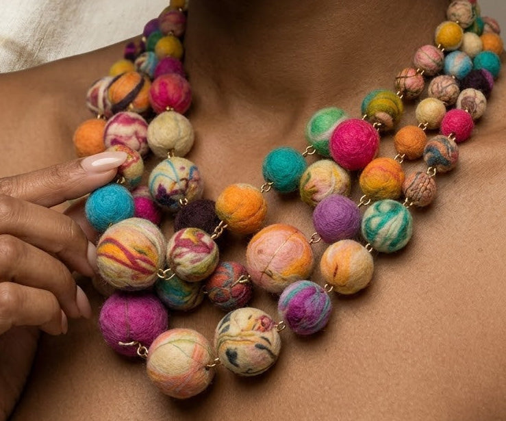 Colorful beaded necklace on a model neck with a glass of champagne and spoon in the background. ZoharasVogue 