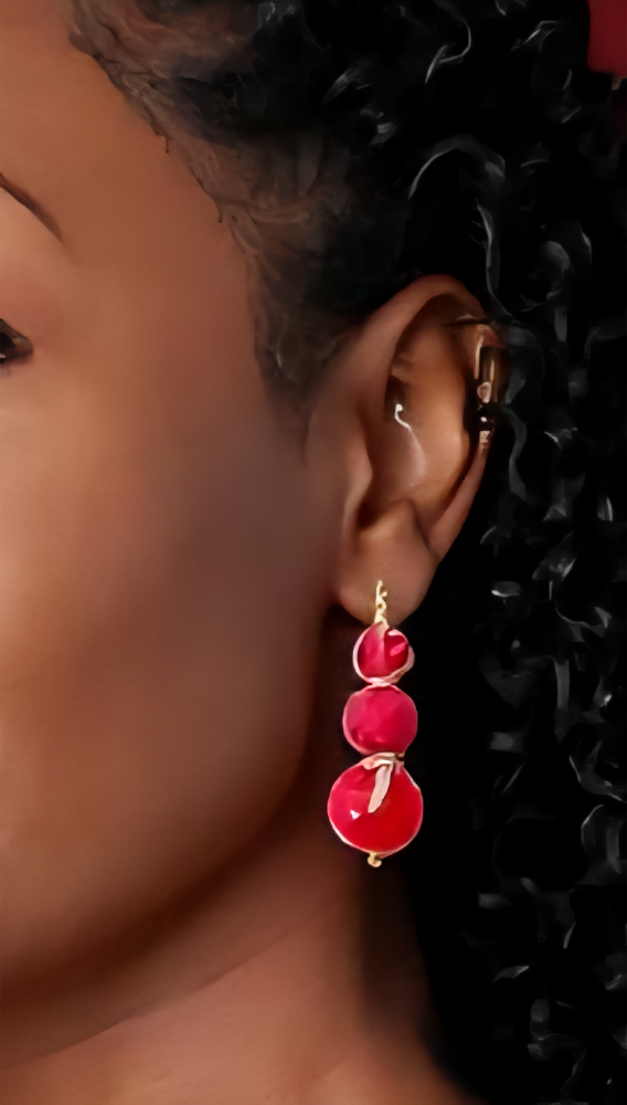 Close-up of handcrafted pink beaded earrings made from recycled sari fabric and wood, hanging against a neutral background