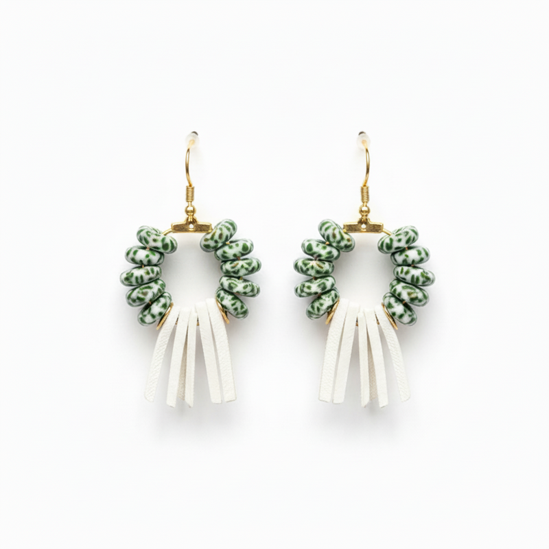 The model wearing earrings with green wreath tops and white fringe on a white background_Zoharas Vogue
