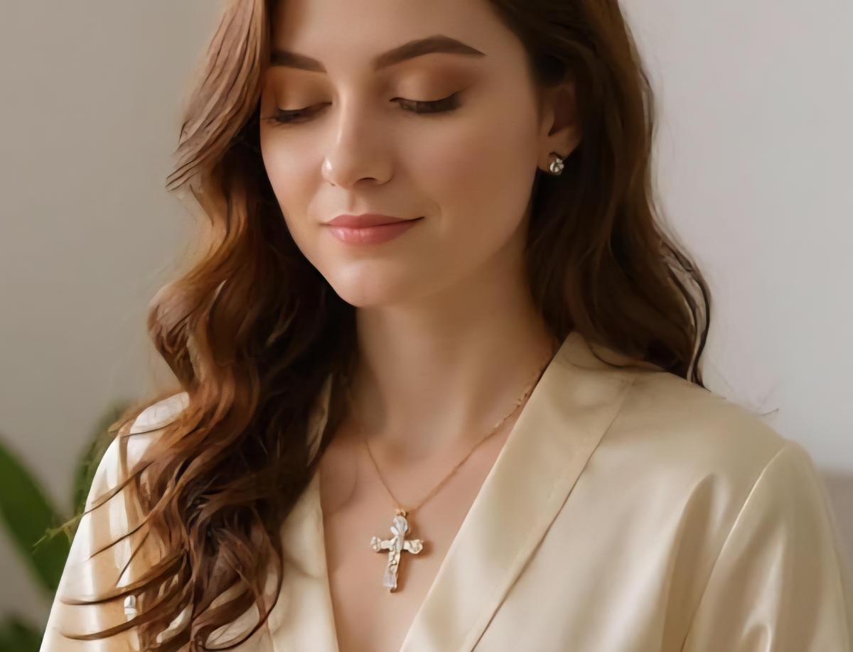 Woman wearing a necklace with a cross pendant in a softly lit room.