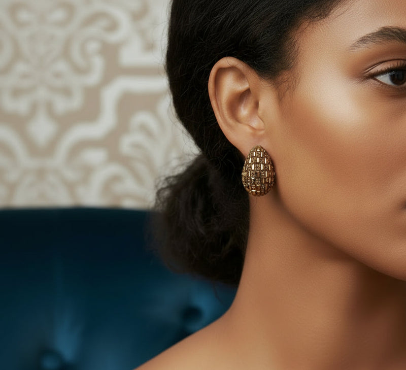 Close-up of a Model wearing a gold earring with a textured design.