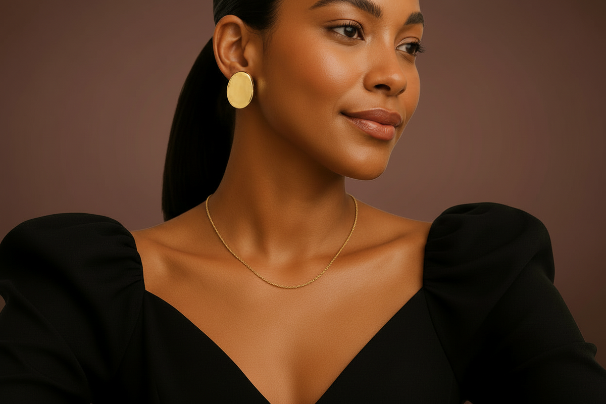 Model wearing gold earrings and necklace against a brown background