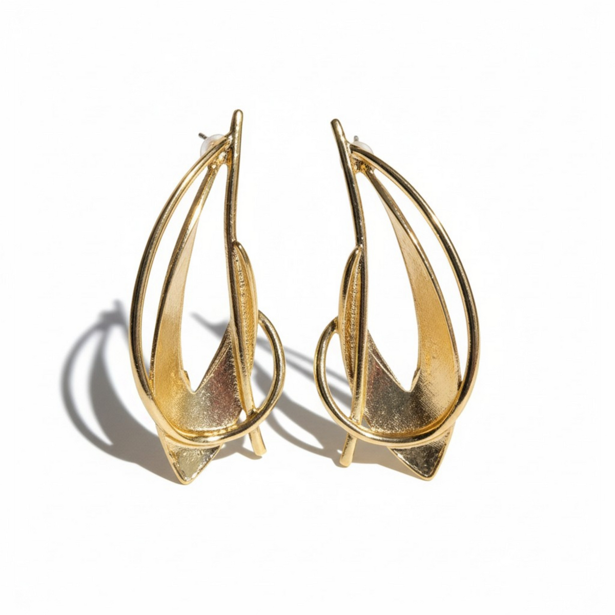 Modern gold sculptural hoop earrings with an abstract, geometric multi-layered design and a pointed interior shape. Casts a sharp shadow on a white background. ZoharasVogue 