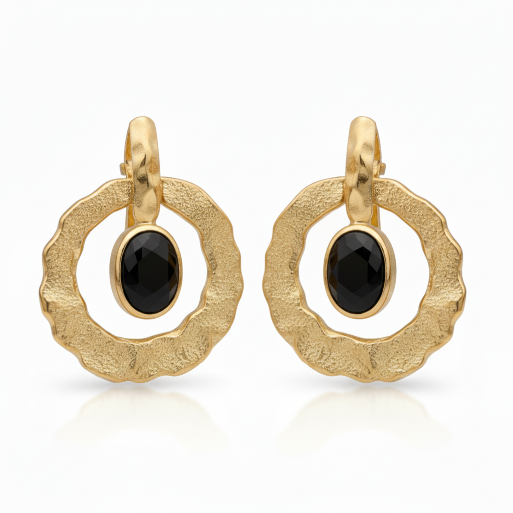Gold earrings with black gemstones on a blurred background