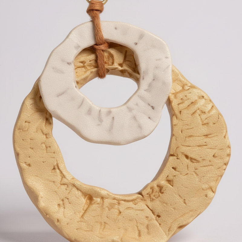 Decorative ring with textured surface and brown cord on a light gray background