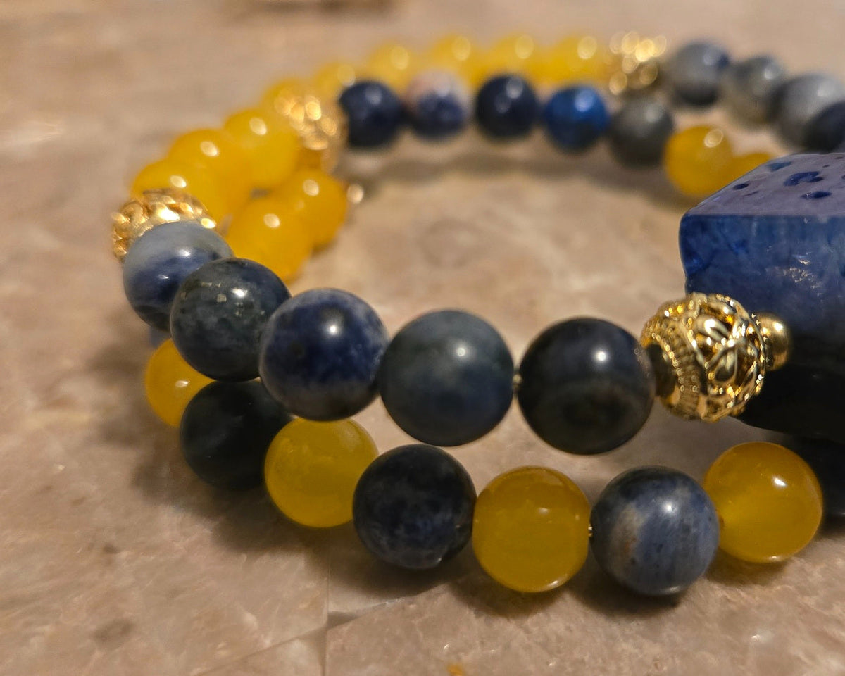 Azure Solstice Bracelet close-up showing dark blue and yellow beads, marbled cube and gold-tone spacers.