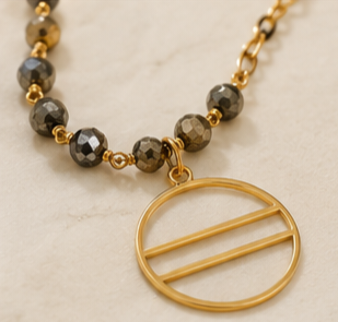 The Eclipse Necklace Handcrafted pyrite gemstone necklace and bracelet featuring faceted rondelle beads, gold chain links, and an open circle pendant in a modern luxury design.- ZOHARAS VOGUE