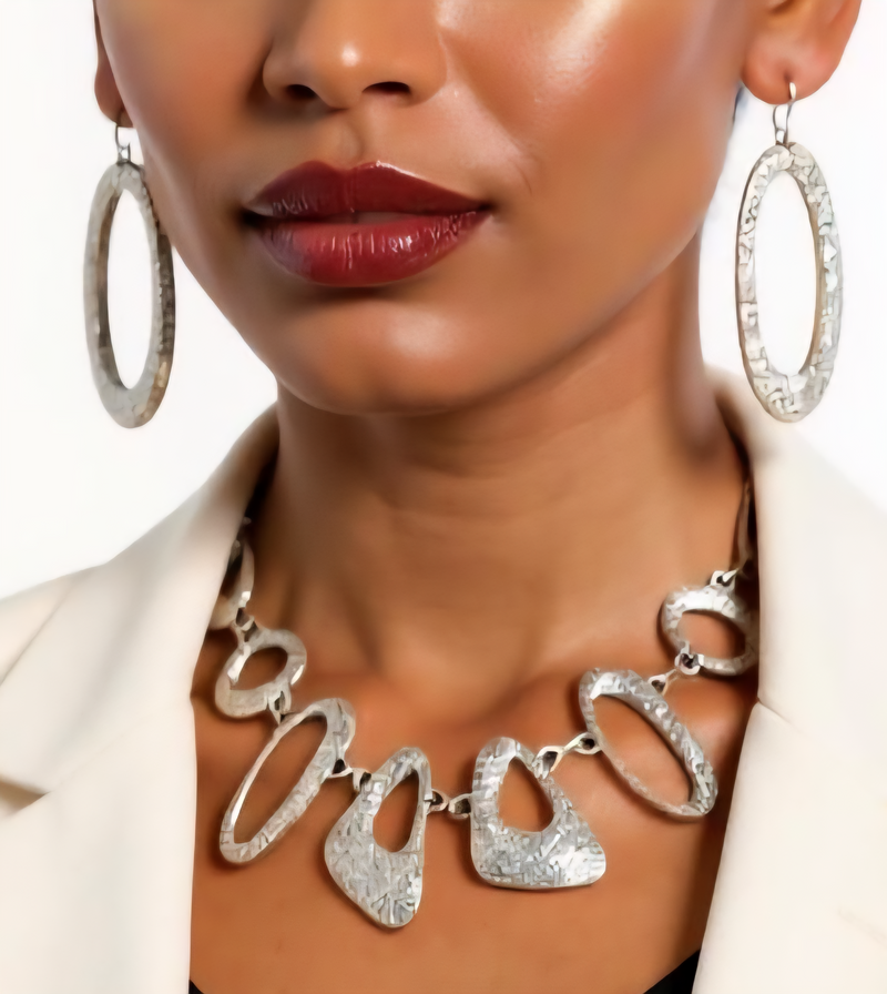 Close-up of a woman wearing a silver necklace and hoop earrings with a blurred background