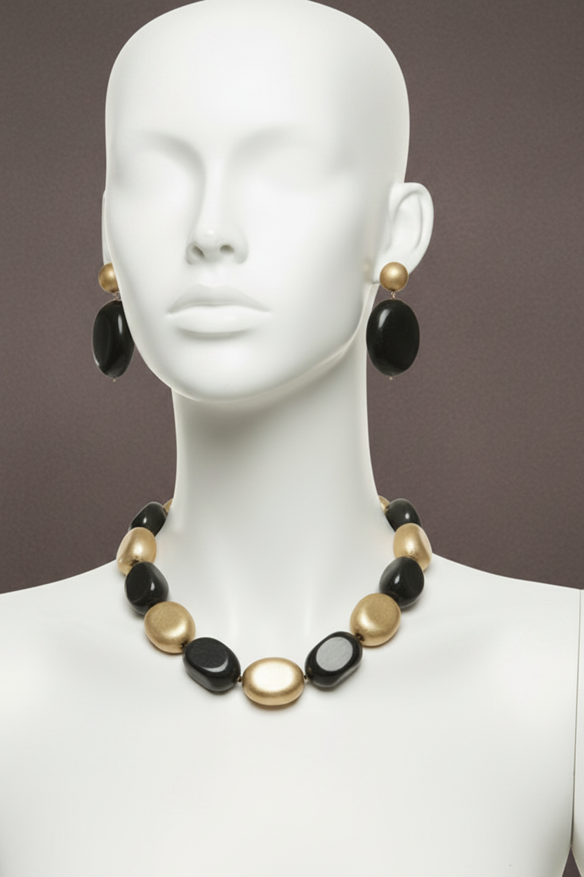 The Dior Statement Earrings, a chunky beaded necklace with alternating black and matte gold beads on a marble surface. ZoharasVogue