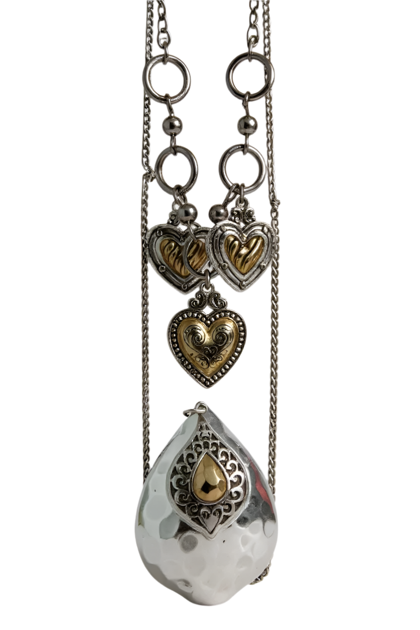 Silver and gold mixed metal necklace with vintage heart charms and a hammered teardrop pendant on layered chains.

